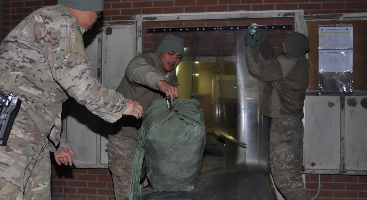 Soldiers loading a duffel at an airport (public-domain U.S. Army photo, Sgt. Eddie Siguenza, 2013)