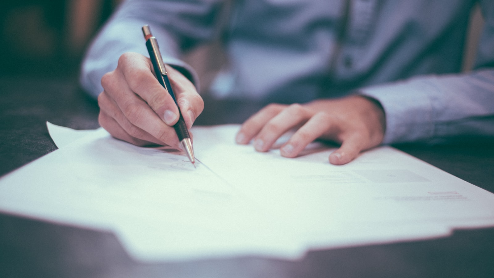 Person reviewing and signing documents at a desk